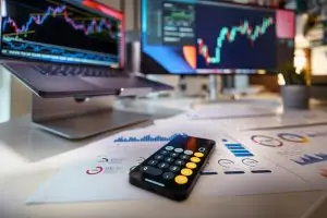 smartphone calculator on desk with financial charts behind